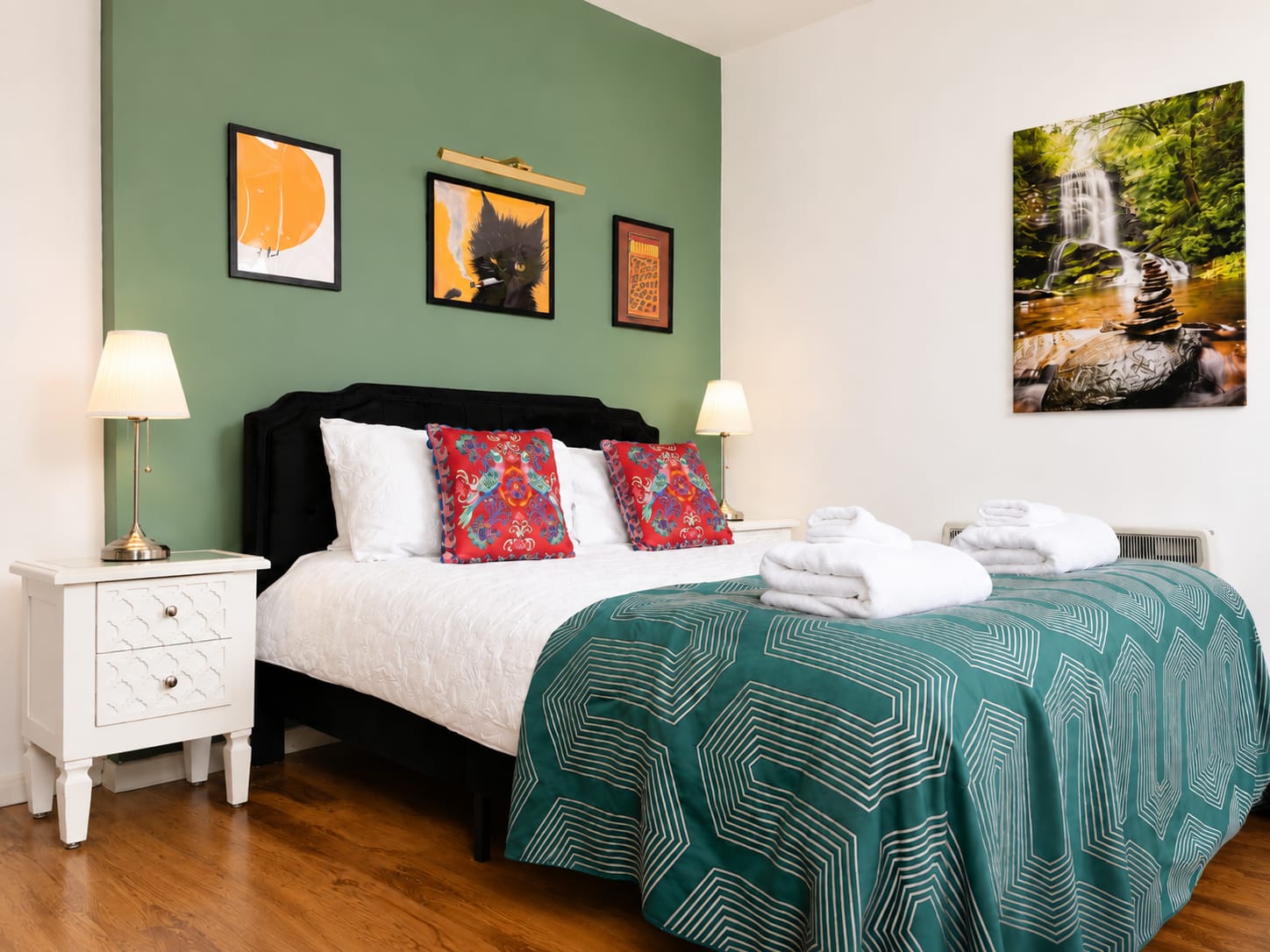 Double bed with floral cushions against a green accent wall