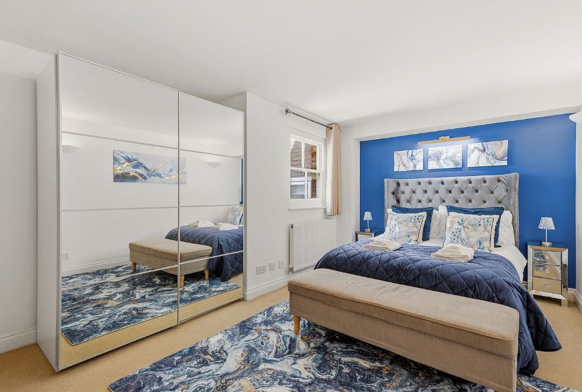 Bedroom with double bed, mirrored wardrobes and blue accent wall