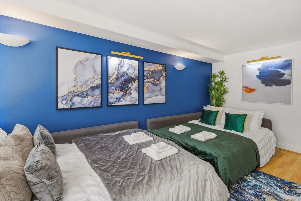 Two comfortable beds with fresh linen and towels against a blue feature wall
