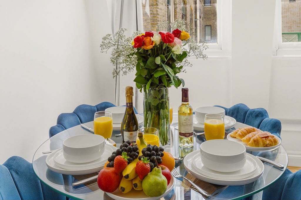 Dining table dressed with fresh fruit, flowers and tableware