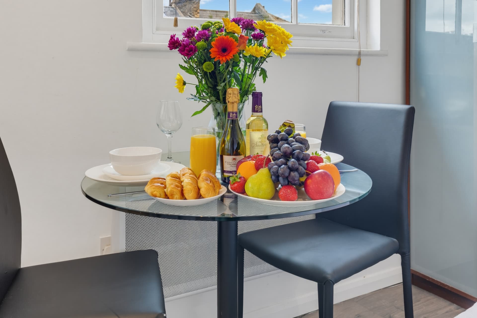 Glass dining table set for two beside the window